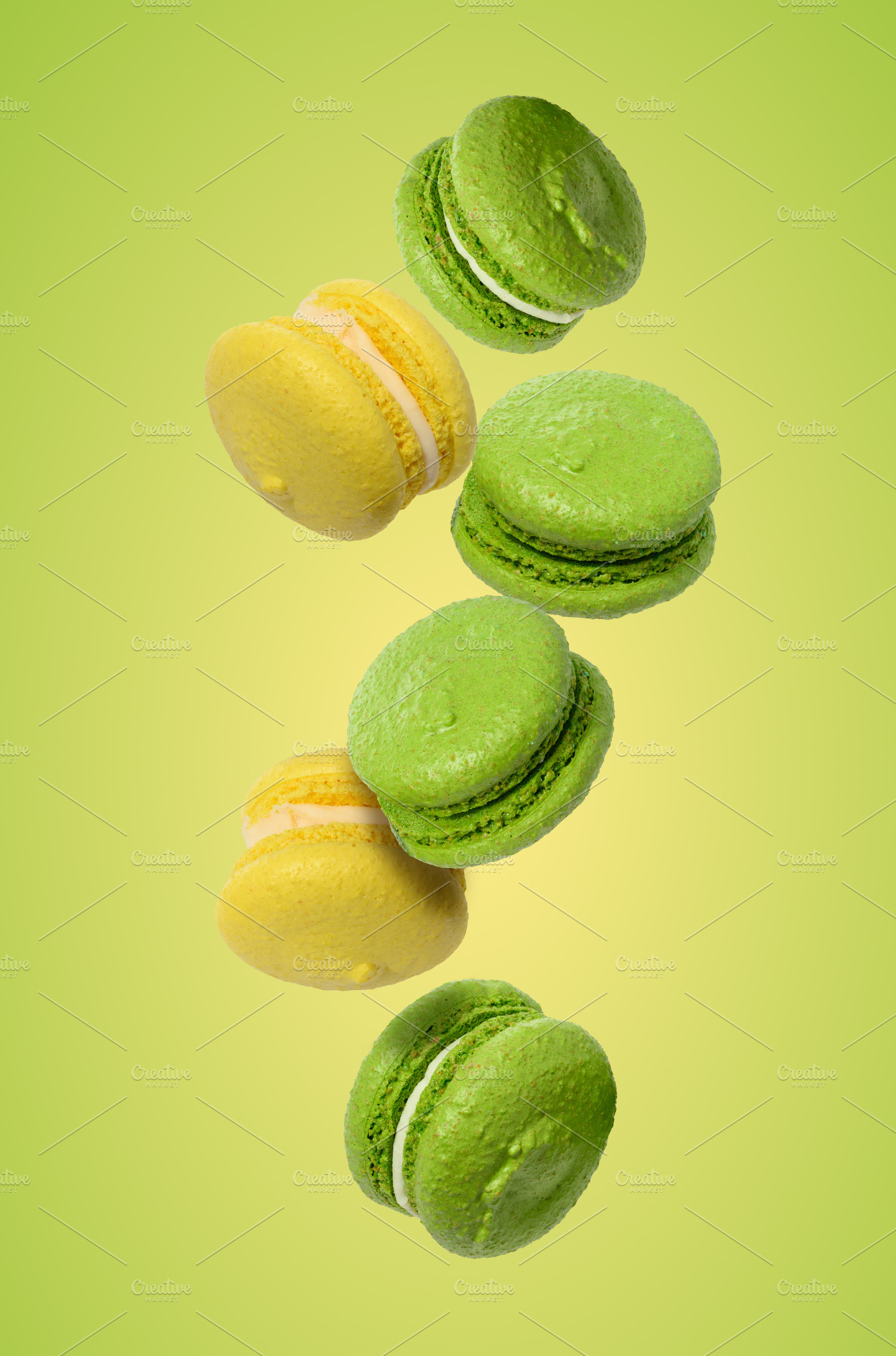 Levitating green and yellow macarons on a light green background, a Food & Drink Photo by ndanko