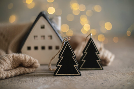 Ceramic house insulated by warm sweater and black tree decor on background with, a Holiday Photo by Anikona
