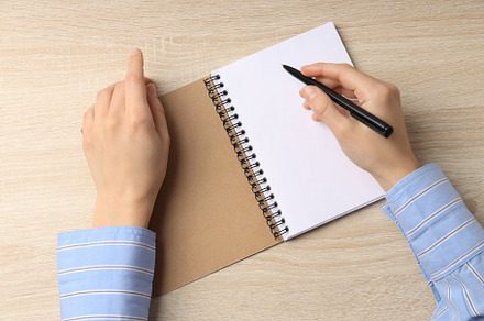 Female hands writes in blank notebook on wooden table, a Business Photo by AtlasStudio PRO