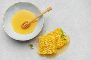 Honeycomb, honey dipper and bowl of honey on kitchen table, a Food & Drink Photo by Olena Rudo