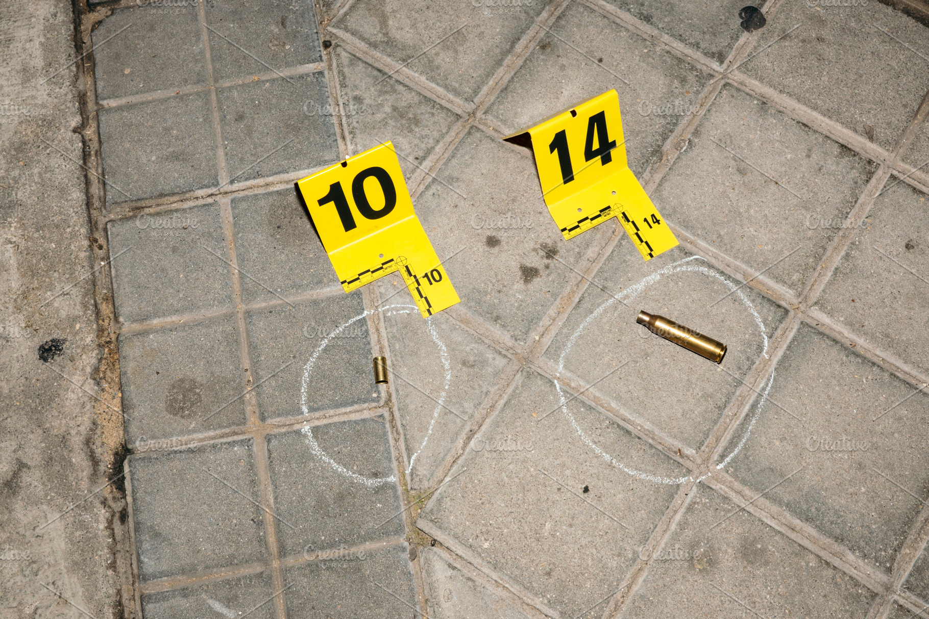 Evidence markers on pavement at crime scene with bullet casings, an Industrial Photo by karrastock