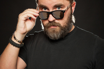 A handsome, strong man with a stylish hairstyle and beard dresses sunglasses in the Studio on a black background, a Person Photo by Budarinphoto