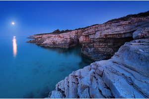 Rocky sea coast and full moon at, a Nature Photo by den-belitsky