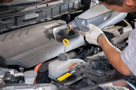 Servicing mechanic pouring new oil lubricant into the car engine featuring, an Industrial Photo by Twinster Photo