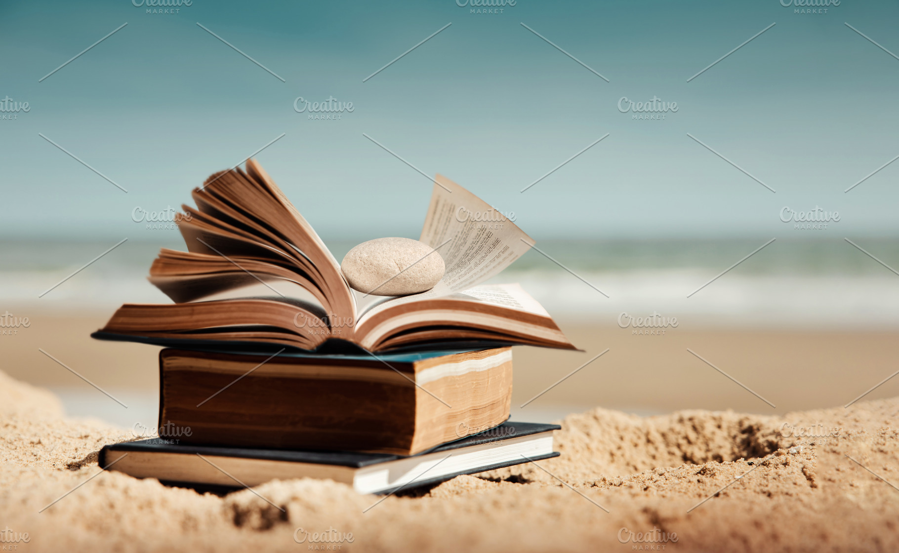 Open book placed on sandy beach with ocean background. Concept o, a Photo by salmon.black