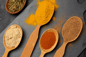 Assorted ground spices in wooden spoons, turmeric, paprika, nutm, a Food & Drink Photo by ndanko
