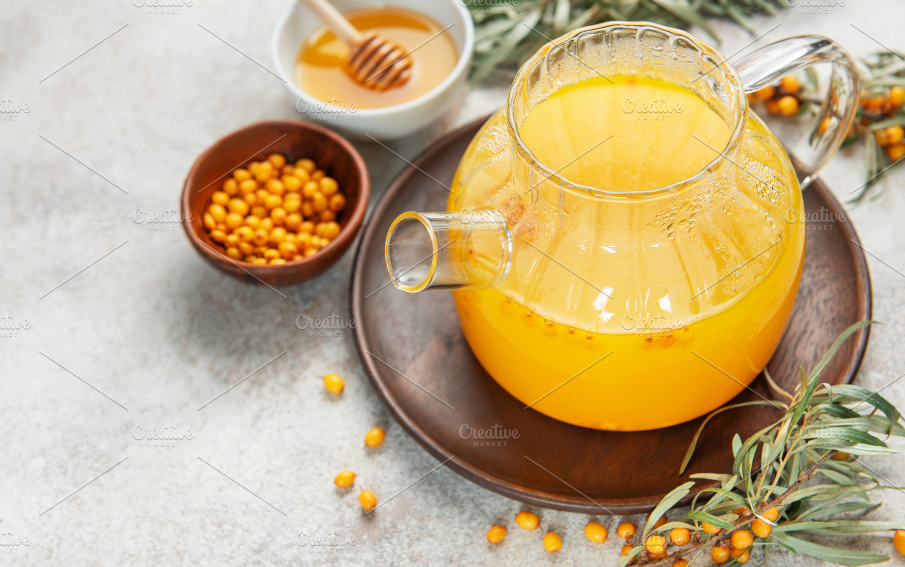 Sea buckthorn hot drink in glass teapot on wooden tray, a Food & Drink Photo by Olena Rudo