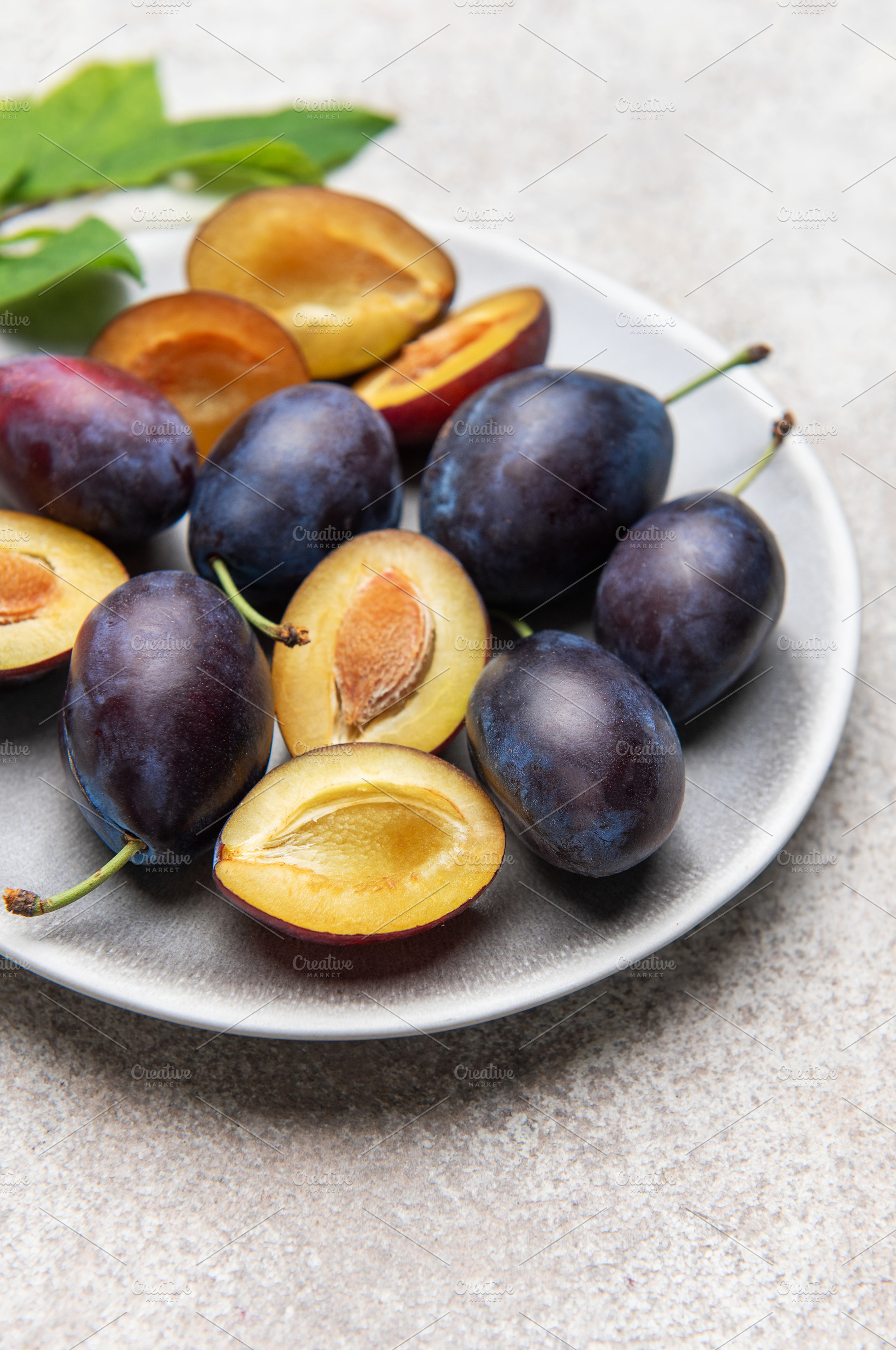 Fresh plums on plate showing halved fruit composition, a Food & Drink Photo by Olena Rudo