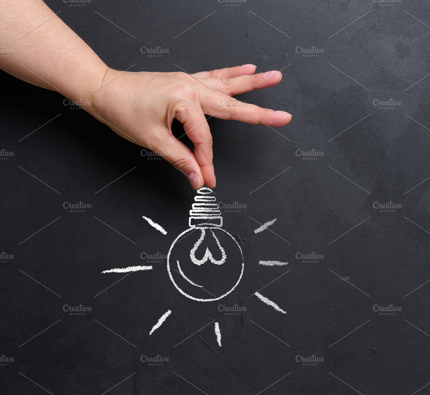 A hand holds a light bulb drawn in chalk on a black chalk board., a Business Photo by ndanko