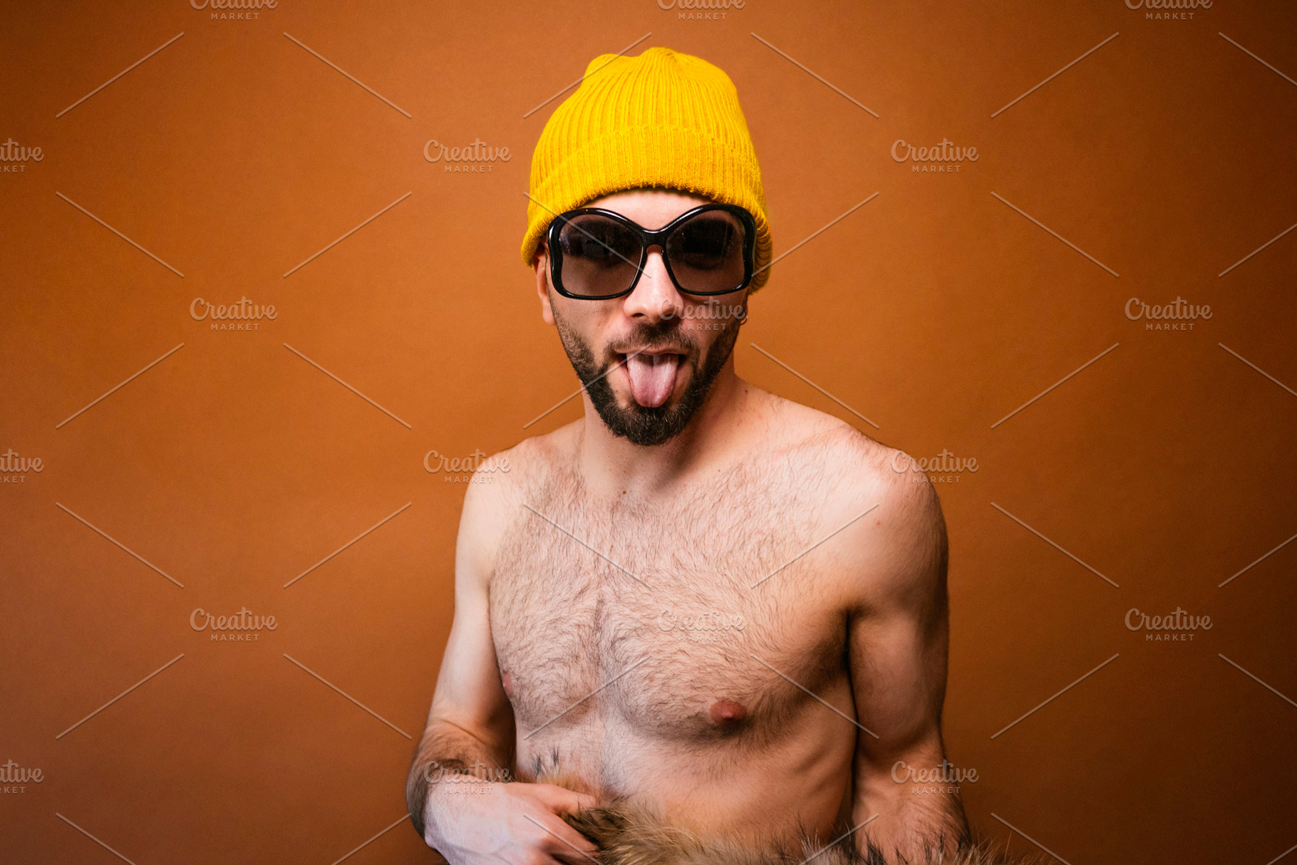 Young adult man wearing beanie sticking tongue out, a Photo by karrastock