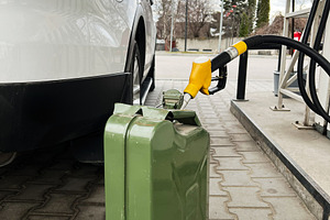 Green metal container and car fueling at a gas station under cloudy skies, a Photo by AS photostudio