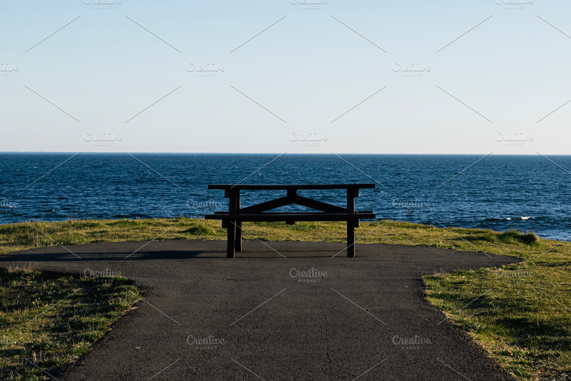 Scenic coastline with bench overlooking waves in Akranes, Iceland under clear s, a Photo by AS photostudio