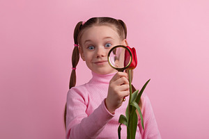 Smiling young girl holding magnifying glass to a tulip blossom a, a Nature Photo by Ales Munt