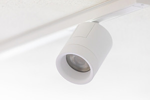 White cylindrical spotlight hanging from ceiling track lighting system, an Architecture Photo by Antonio Gravante Market