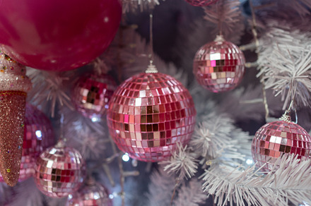 Closeup of shiny pink baubles hanging on illuminated Christmas tree, a Photo by andreonegin market