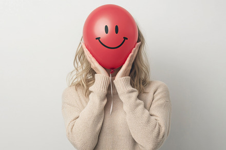 Woman Hiding Face with Smiley Balloon for Playful Expression