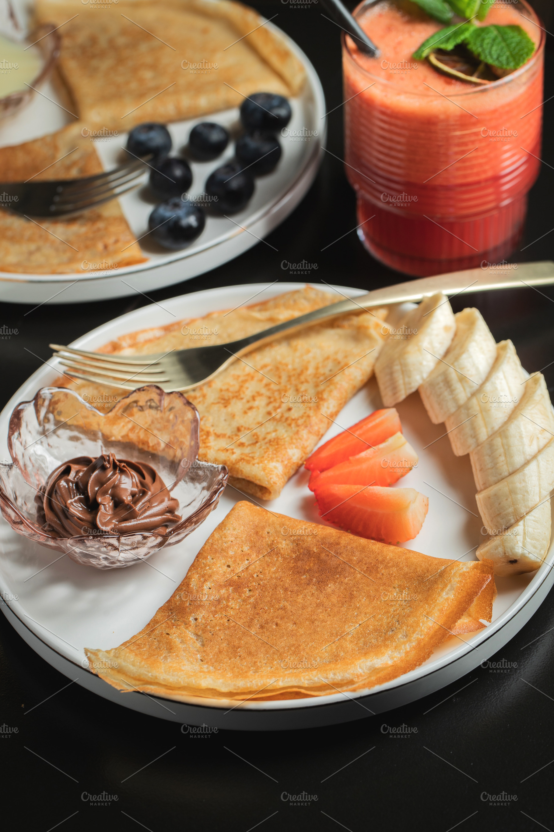 A plate of crepes filled with chocolate spread and topped with banana slices an, a Food & Drink Photo by Budarinphoto