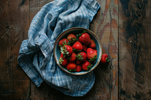 Flat lay of red strawberries in bowl with napkin on wooden table, a Food & Drink Photo by AlyaAnd