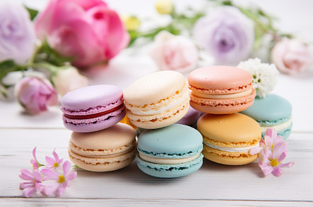 Colorful macarons dessert in box with flowers on wooden background, a Food & Drink Photo by AlyaAnd