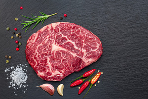 Raw ribeye steak on stone black serving plate. Flat lay., a Food & Drink Photo by Volff
