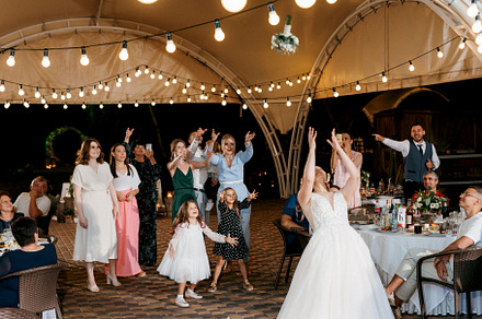 bride in a white dress throws a wedding bouquet