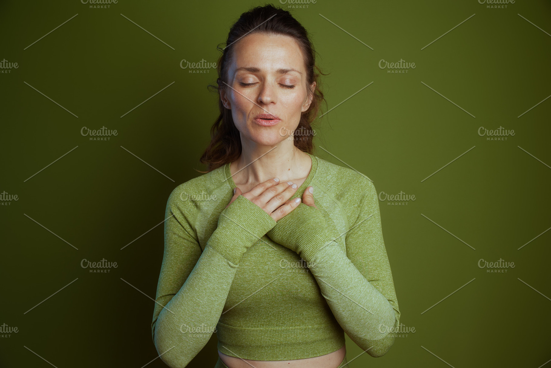 Serene woman in green, eyes closed, a Person Photo by Alliance Images