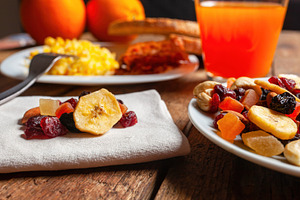 Dried fruit mix, orange juice and scrambled eggs composing a healthy breakfast, a Food & Drink Photo by Antonio Gravante Market