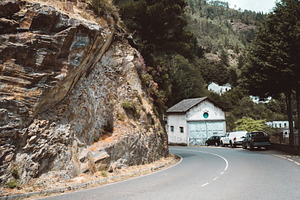 Mountain road by cliff and building, a Transportation Photo by SkyNext