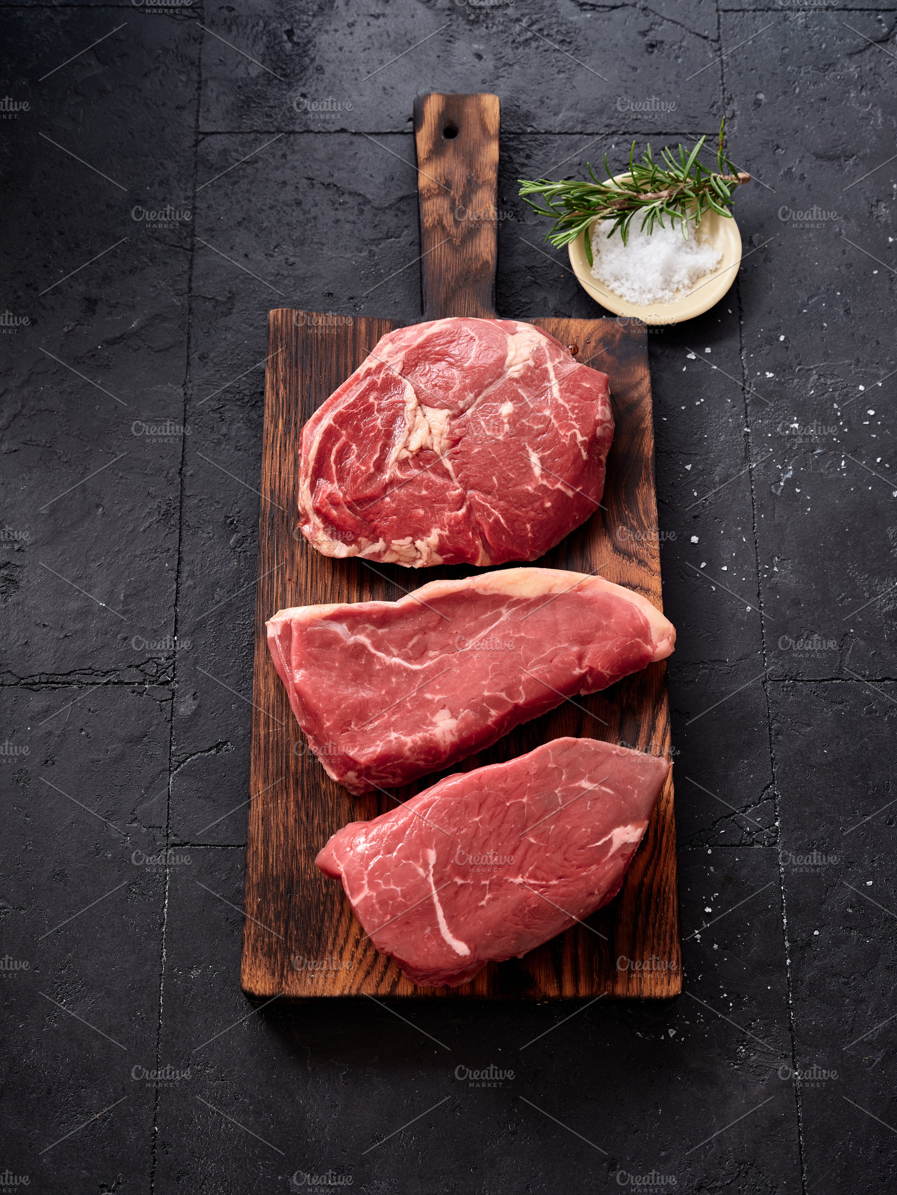 Raw rib-eye, roast beef, flank and rump steak displayed on a wooden board with, a Food & Drink Photo by Asya Nurullina
