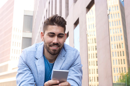 Portrait of Handsome young man smiling when he is using his mobile phone, a Person Photo by RF Images