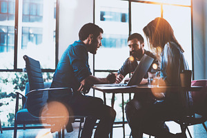 Teamwork brainstorming process.Young man working together with partners in modern office loft.Business startup concept.Blurred background.Flares.