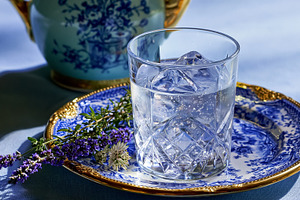Refreshing iced water with lavender and herbs on an ornate blue and white plate, a Photo by Studio ANNA