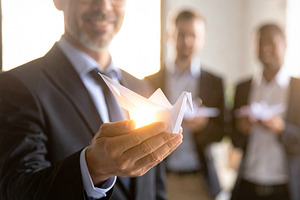 Business leader holding a glowing origami bird close to chest, a Technology Photo by DanFLCreativo