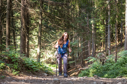 Exhausted woman with poles hiking through the forest in mountains, a Sports & Recreation Photo by serkum