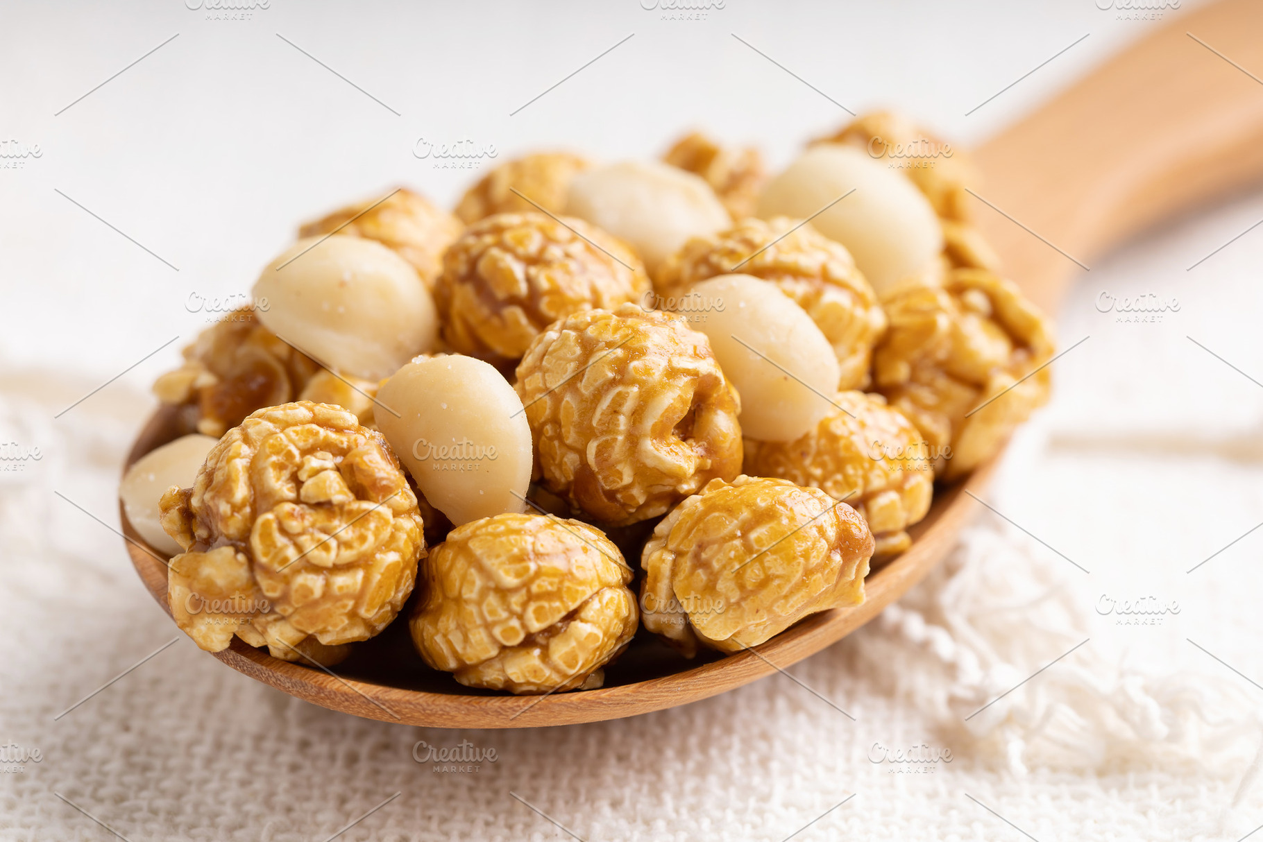 Caramel popcorn with macadamia nut in wooden ladle, a Food & Drink Photo by Smith Chetanachan