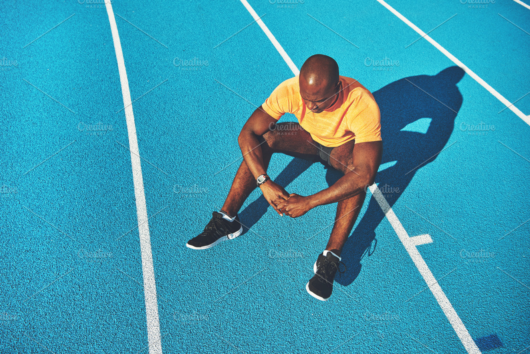 Young runner sitting alone on a running track after training, a Person ...