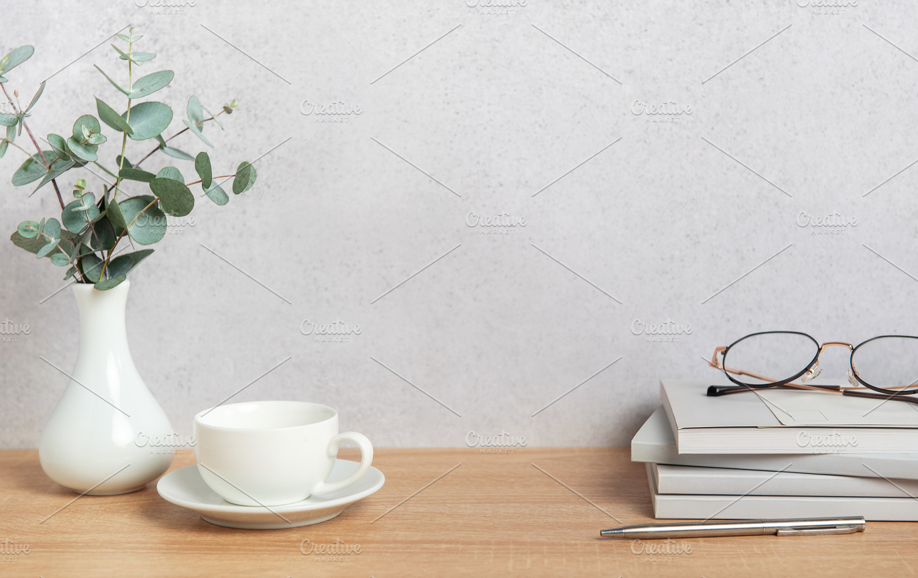 Eucalyptus branches, coffee cup, books and eyeglasses resting on, a Background Photo by Olena Rudo
