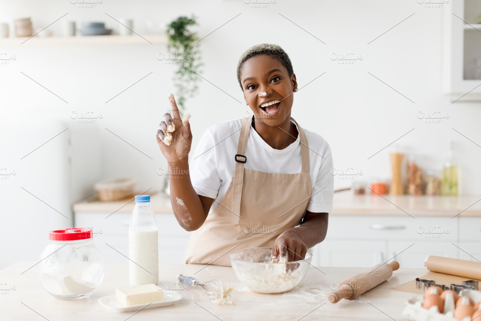 Laughing millennial african american woman in apron prepares dough for baking a, a Person Photo by Prostock-Studio