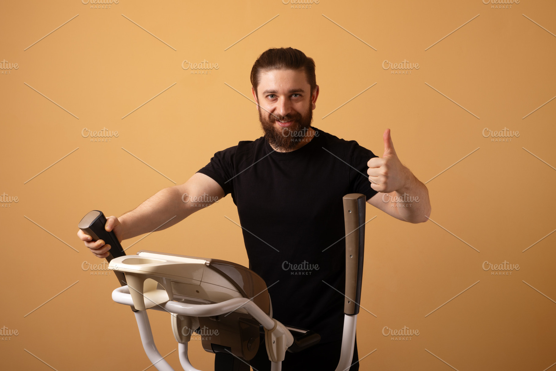 Smiling man in black shirt using elliptical machine and showing, a Person Photo by Ales Munt