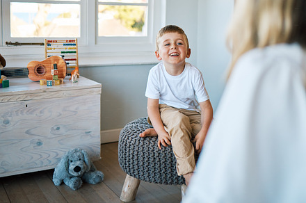 An adorable little boy sitting on a chair while talking to a caucasian therapist. Cute little boy talking to a psychologist. Child checking in with a counsellor at a foster home before being adopted, a Photo by Peopleimages.com