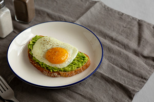 Homemade Avocado Toast with Egg on a Plate, side view. Copy spac, a Food & Drink Photo by LiudmylaChuhunova