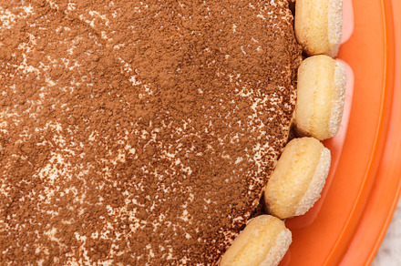 Round tiramisu cake on white wood table sprinkle with cacao powd, a Food & Drink Photo by TanaCh
