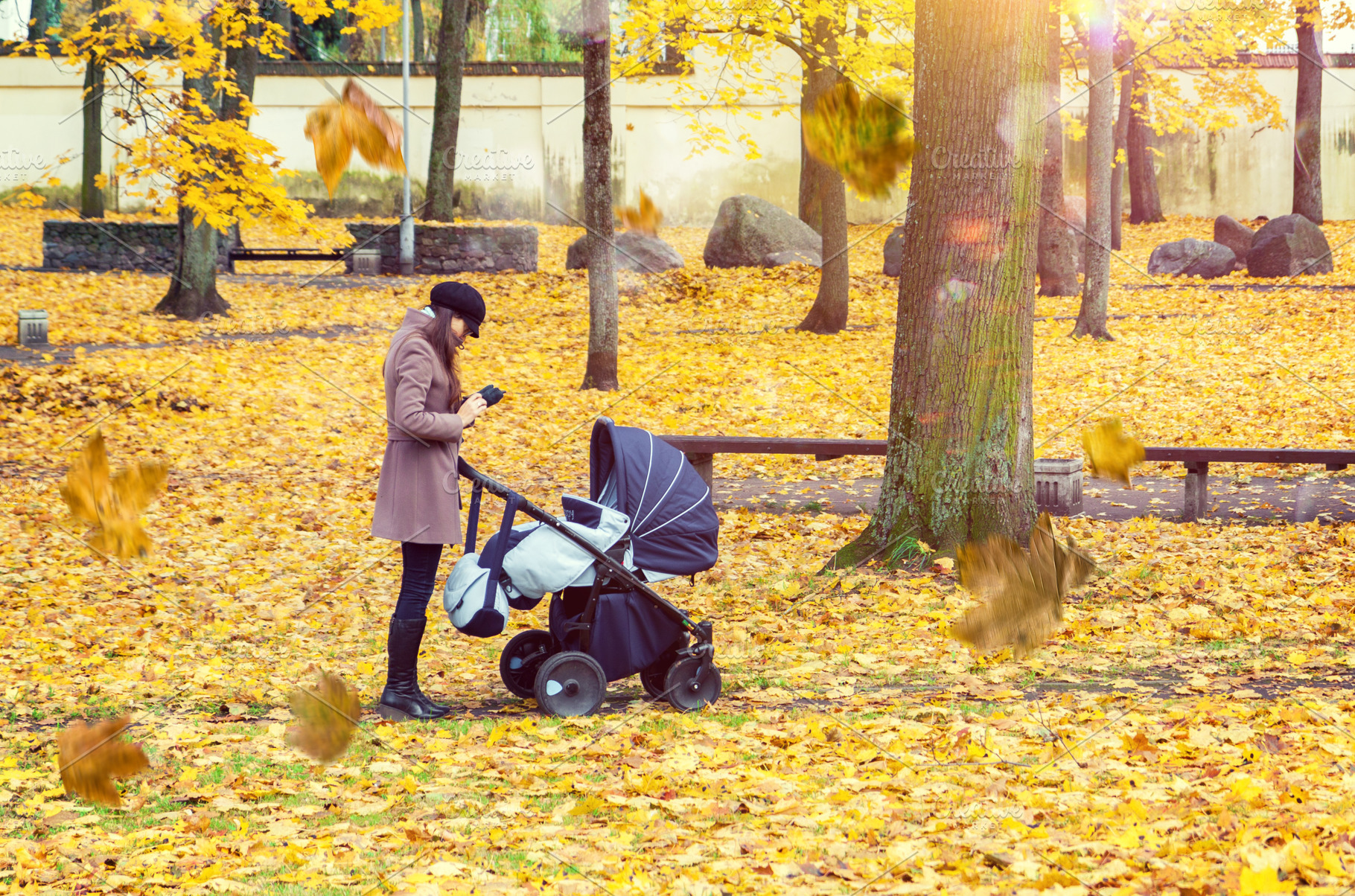 Mother with baby pram in autumn park, a Person Photo by BOOCYS