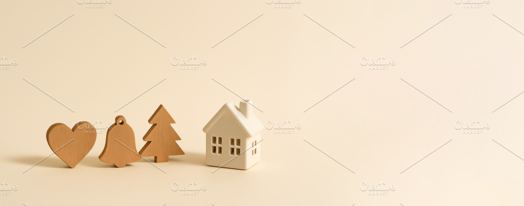 Wooden holiday symbols heart, bell, tree, and house on beige bac, a Photo by Dvoevnore photos