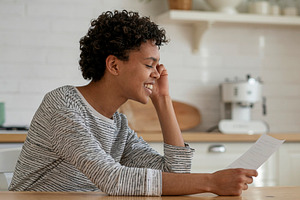 Smiling person holding paper at kitchen counter, a Photo by DanFLCreativo