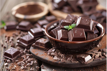 Dark chocolate chunks piled in bowl, a Food & Drink Photo by Ylivdesign
