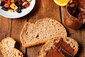 Spreading chocolate cream on whole wheat bread for breakfast with orange juice, a Food & Drink Photo by Antonio Gravante Market