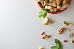 Heap of peanuts with skin in clay bowl on table, a Food & Drink Photo by Davizro's Market