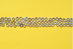 Horizontal metal nuts line on yellow, an Industrial Photo by Gladkov photography