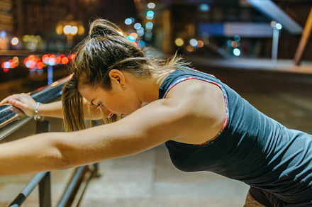 Portrait of female young athlete resting over banister after training at night, a Sports & Recreation Photo by davidpereiras